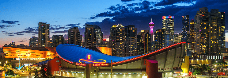 A view of the Scotiabank Saddledome with a skyline of Calgary, Canada, during twilight.