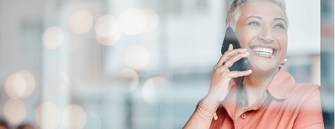A smiling woman with short gray hair is on the phone, looking happy and engaged.